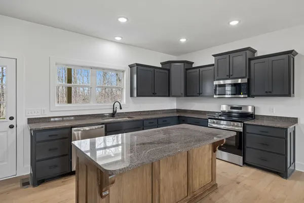 a kitchen with stainless steel appliances granite countertop a sink stove microwave and refrigerator