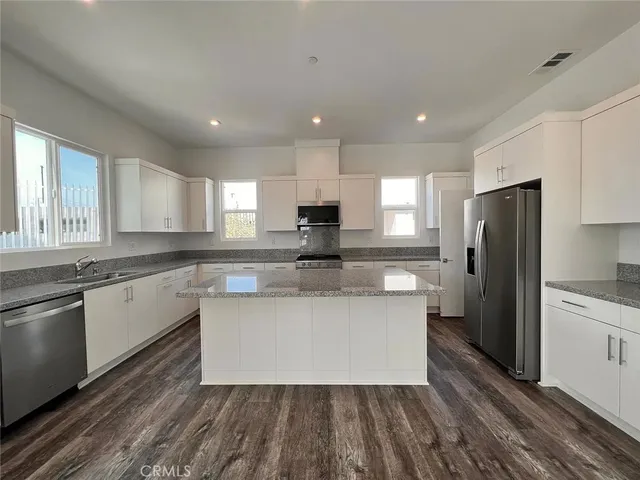 a large kitchen with stainless steel appliances kitchen island granite countertop a stove a sink and a refrigerator