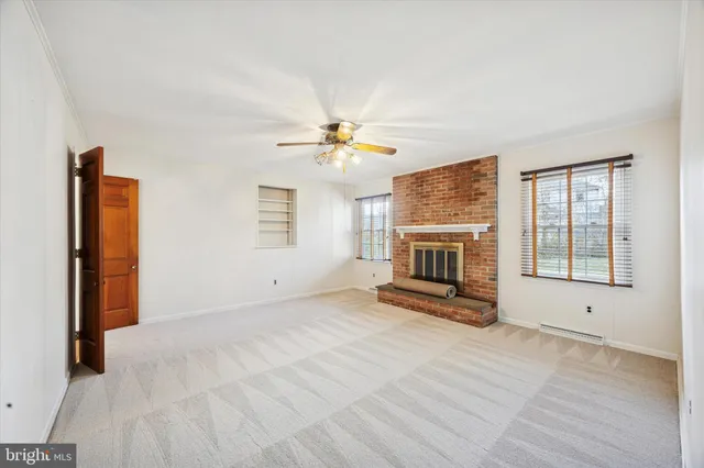 an empty room with windows and fireplace