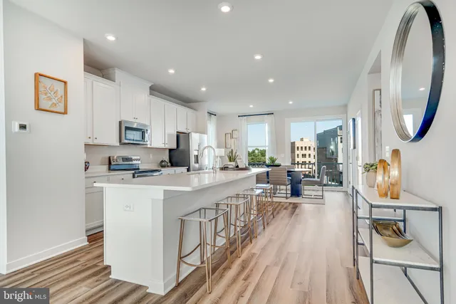 a kitchen with stainless steel appliances granite countertop a refrigerator a stove top oven a sink dishwasher and white countertops with wooden floor