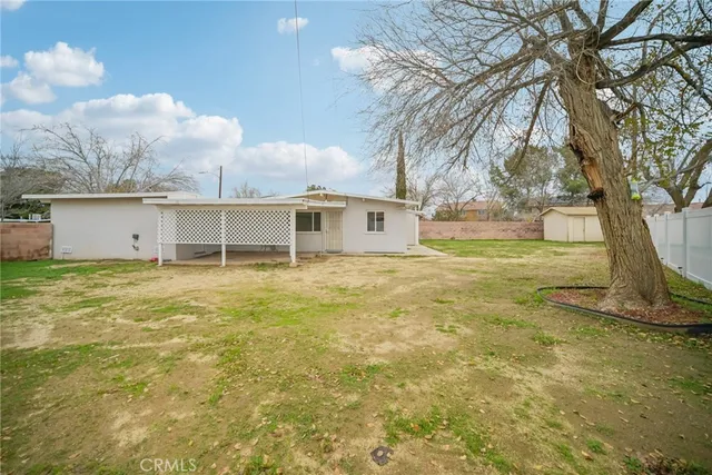 a view of a house with backyard and a tree
