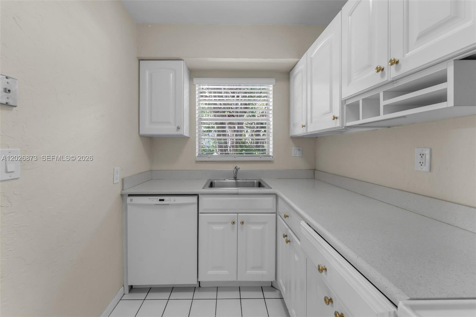 5590 Southwest 78th Street, Unit 133B Miami, FL 33143 - Photo 6 of 18 a kitchen with white cabinets appliances a sink and a window
