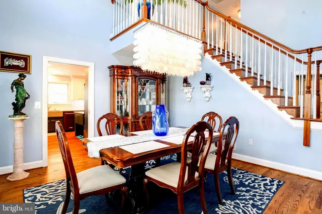 a kitchen with stainless steel appliances granite countertop a stove a refrigerator a sink a dining table and chairs with wooden floor