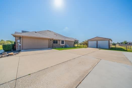 166 Oxford Ranch Road Waxahachie, TX 75167 - Photo 18 of 27 Brick exterior with an attached two-car garage, expansive concrete driveway, and a detached two-bay metal garage