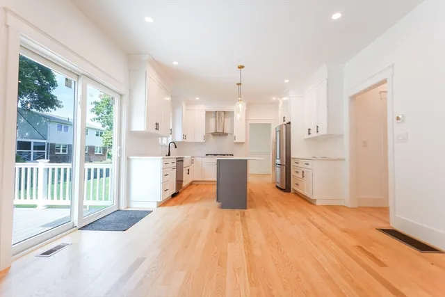 a kitchen with stainless steel appliances kitchen island wooden floor and window
