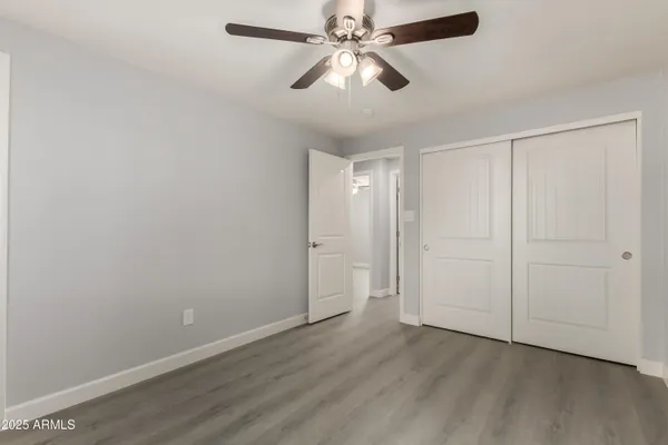 an empty room with wooden floor closet and fan