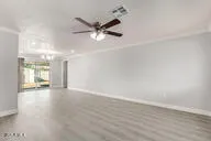 a view of an empty room with wooden floor and a ceiling fan