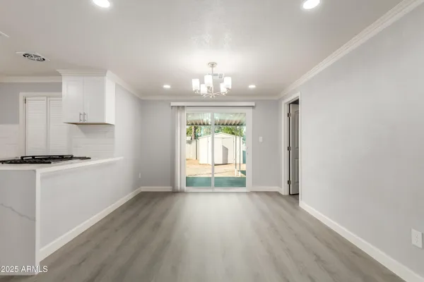 a view of a kitchen and an empty room with wooden floor and a window