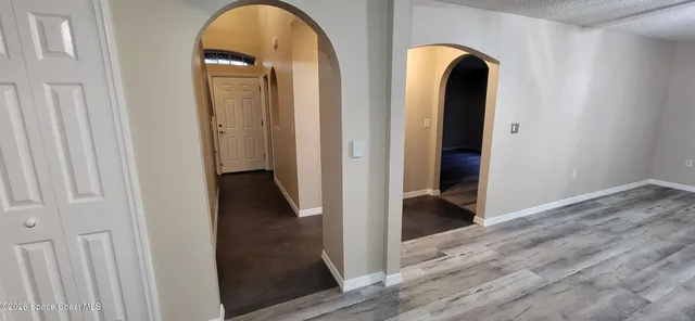 a view of a hallway to a livingroom with furniture wooden floor and window