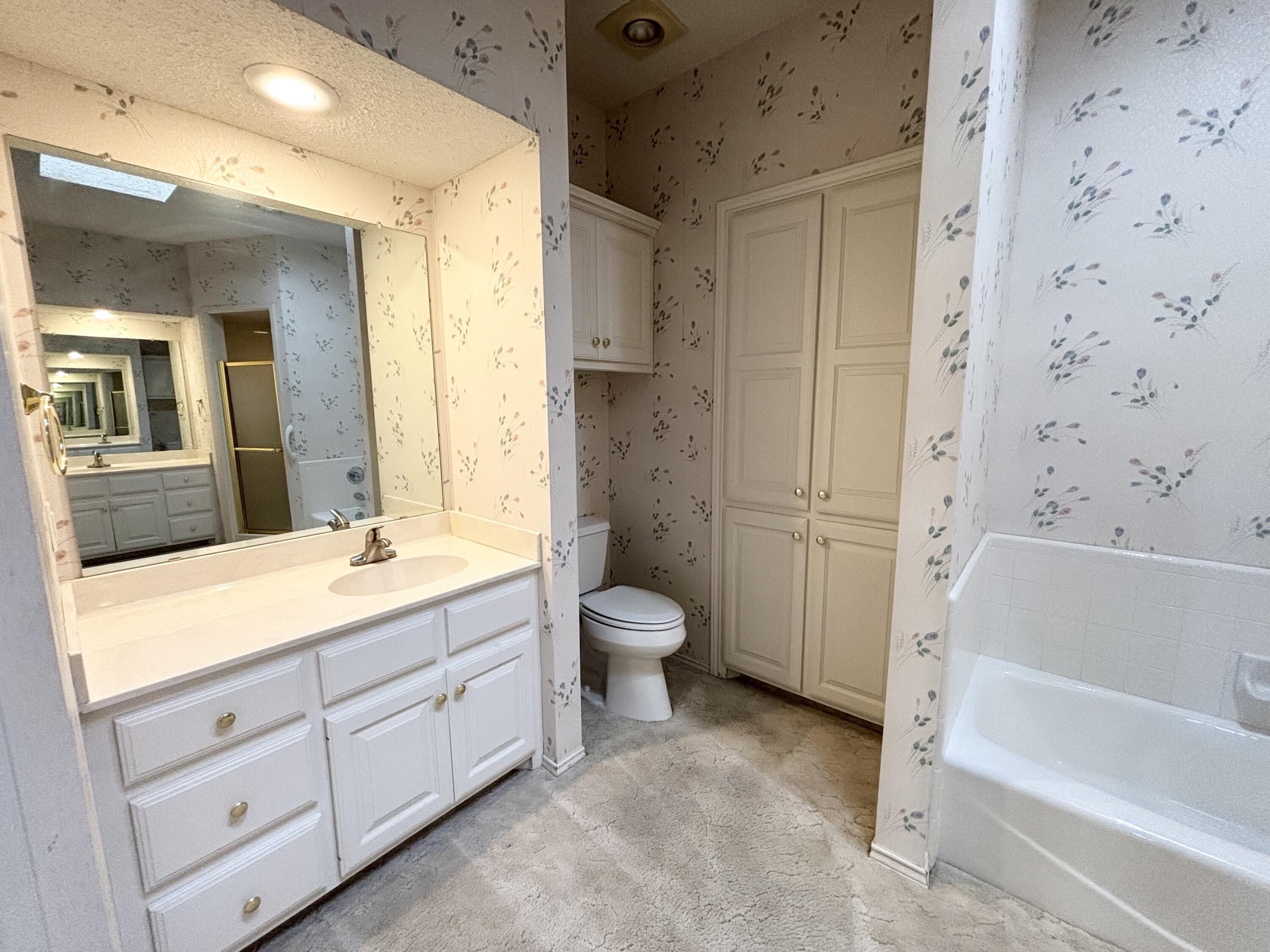6705 Fulton Avenue Lubbock, TX 79424 - Photo 13 of 18 a bathroom with a granite countertop sink toilet a large mirror a bathtub and shower