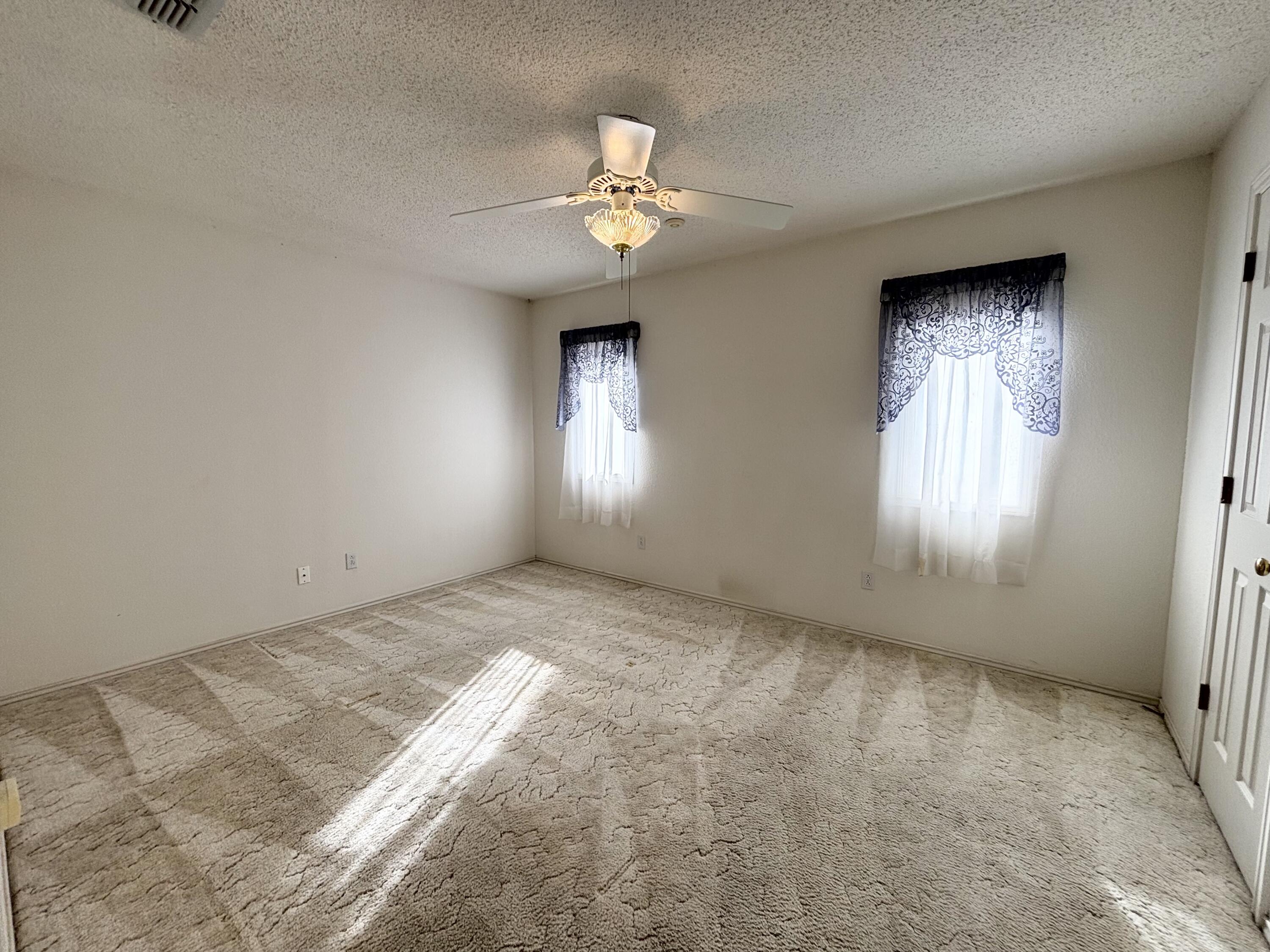 6705 Fulton Avenue Lubbock, TX 79424 - Photo 10 of 18 an empty room with a chandelier fan and windows