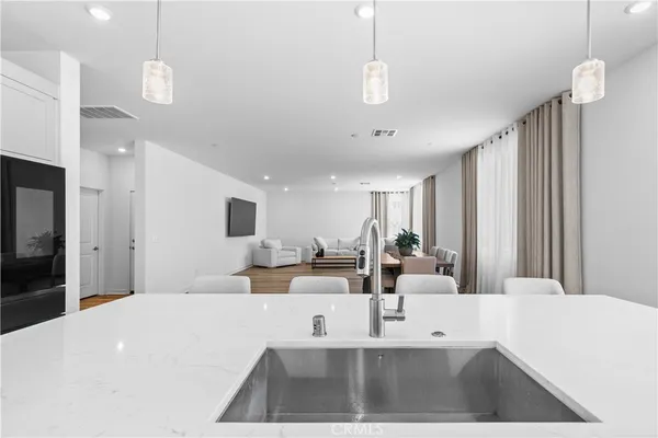 a large white kitchen with a large island sink and refrigerator