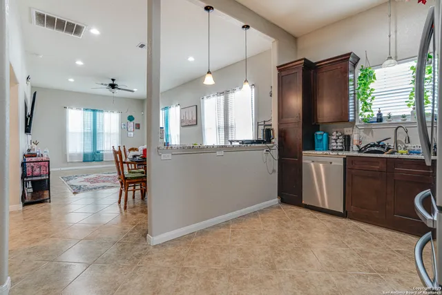 a kitchen with stainless steel appliances a refrigerator a sink dishwasher a dining table and chairs with wooden floor