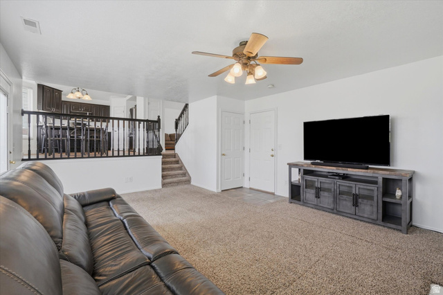 5576 South 4100th Street West Roy, UT 84067 - Photo 17 of 35 Spacious living area featuring neutral carpet flooring and a ceiling fan with integrated lighting