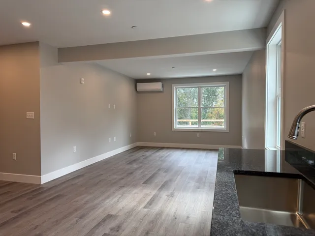 an empty room with wooden floor a ceiling fan and windows