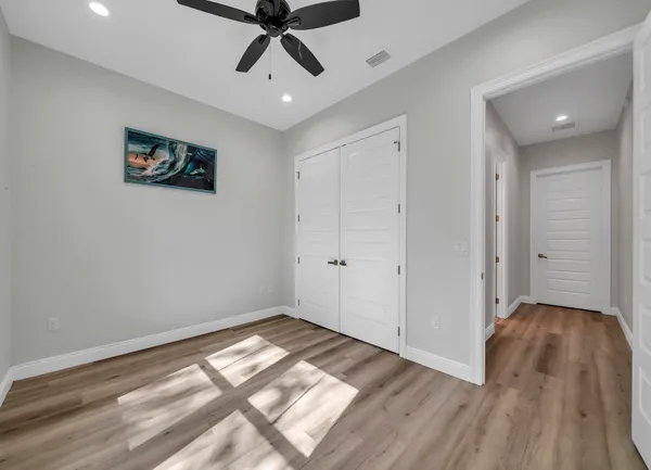 a view of empty room with wooden floor and fan