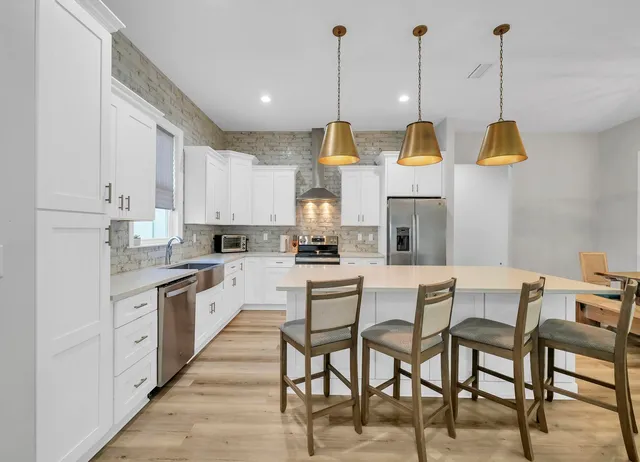 a view of kitchen with stainless steel appliances kitchen island granite countertop a table and chairs