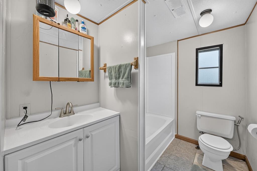 736 Little Joe Road Sanger, TX 76266 - Photo 7 of 17 Full bathroom featuring a single vanity, a built-in medicine cabinet, a toilet, a bathtub with shower surround, and tile-finish flooring