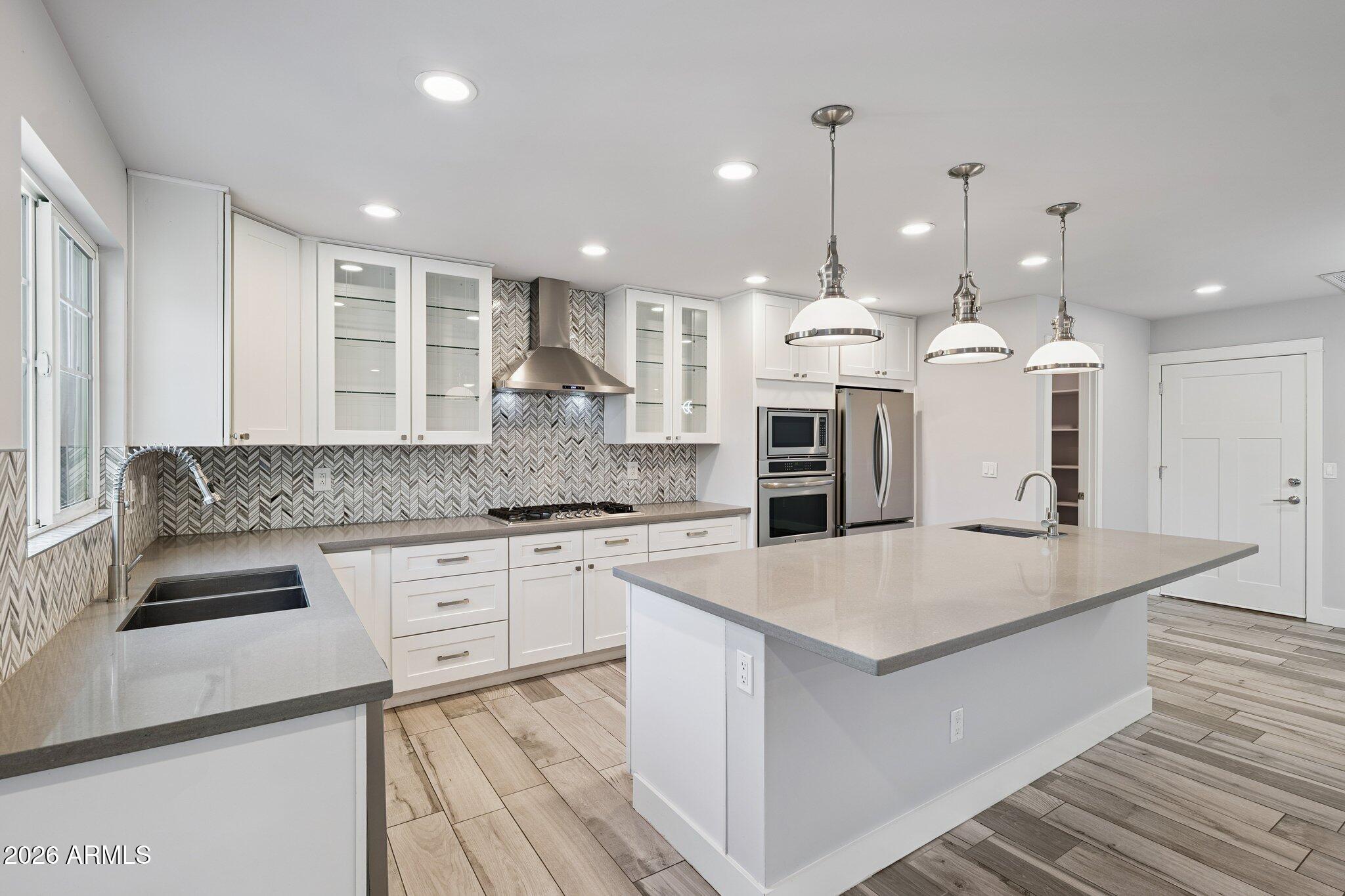 4232 North 19th Place Phoenix, AZ 85016 - Photo 11 of 39 a large kitchen with granite countertop a stove top oven a sink dishwasher and white cabinets with wooden floor