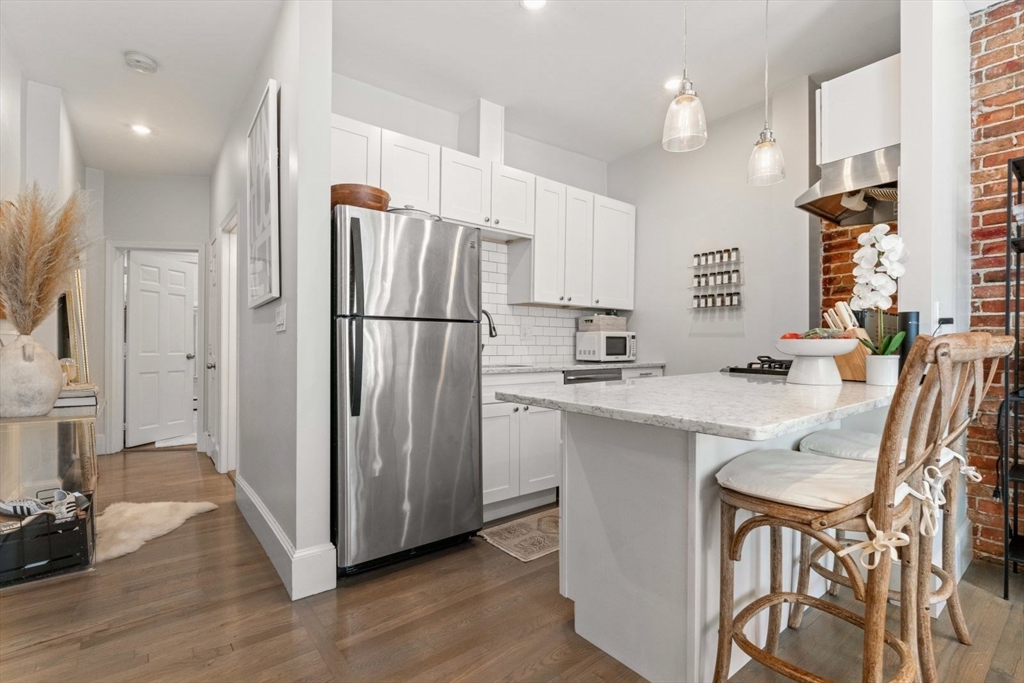 91 Waltham Street, Unit 4 Boston, MA 02118 - Photo 12 of 26 a kitchen with stainless steel appliances a refrigerator a sink dishwasher a stove and white cabinets with wooden floor