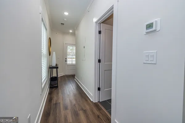 a view of a hallway with wooden floor and a bathroom