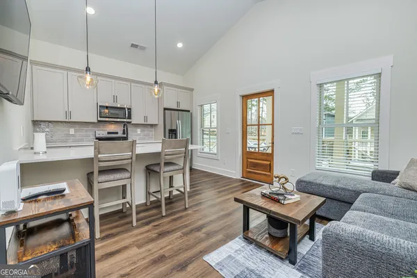 a living room with furniture dining table wooden floor and a window