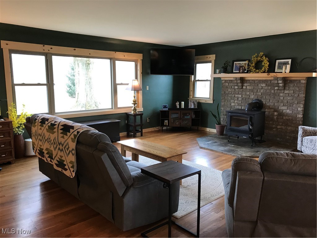 8330 Knauf Road Canfield, OH 44406 - Photo 5 of 34 Living room featuring a wood stove, baseboards, and wood finished floors