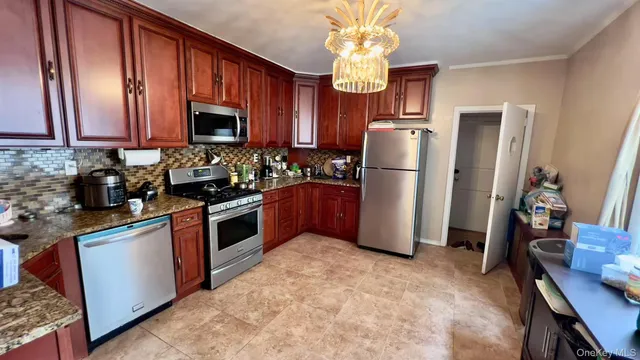 a kitchen with stainless steel appliances granite countertop a refrigerator a stove a sink and a microwave