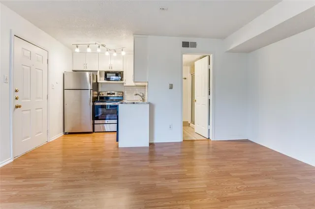 a view of kitchen with refrigerator and wooden floor
