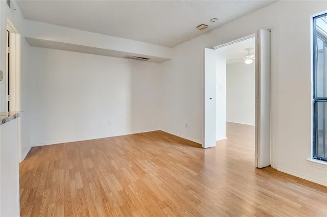 a view of an empty room with wooden floor and a window