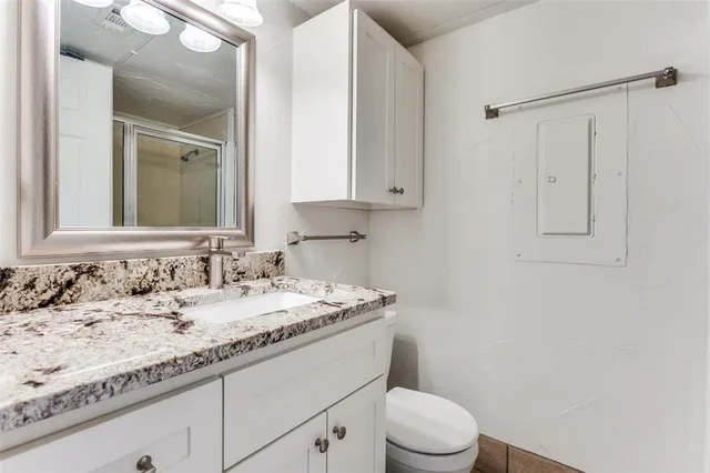 a bathroom with a granite countertop sink toilet and mirror