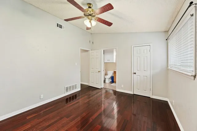 an empty room with wooden floor fan and windows