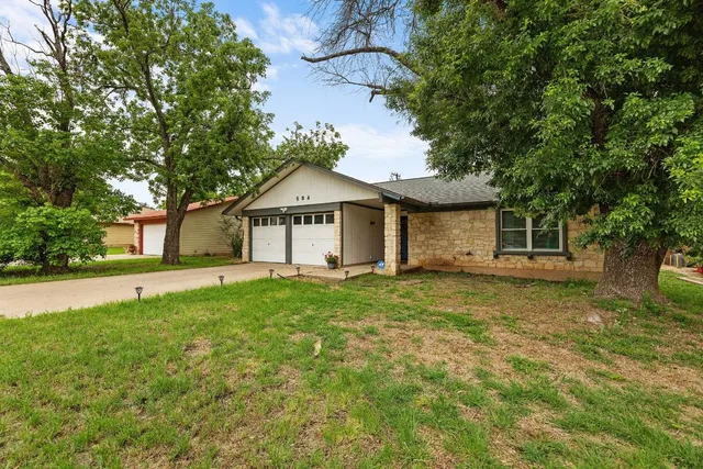 a view of a house with a yard and large tree