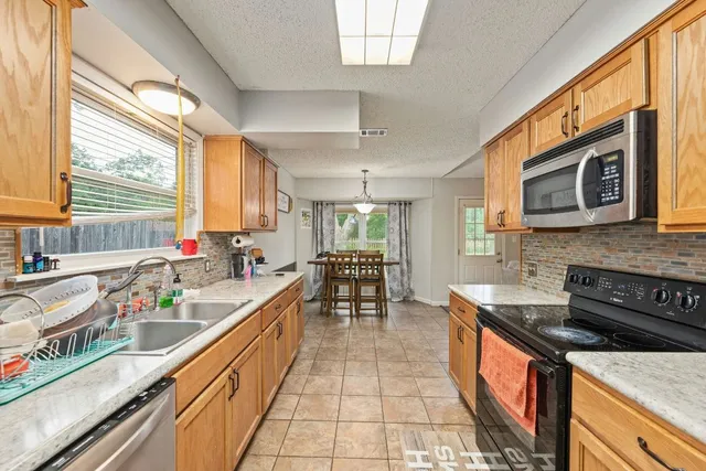a large kitchen with stainless steel appliances granite countertop a stove a sink and a microwave