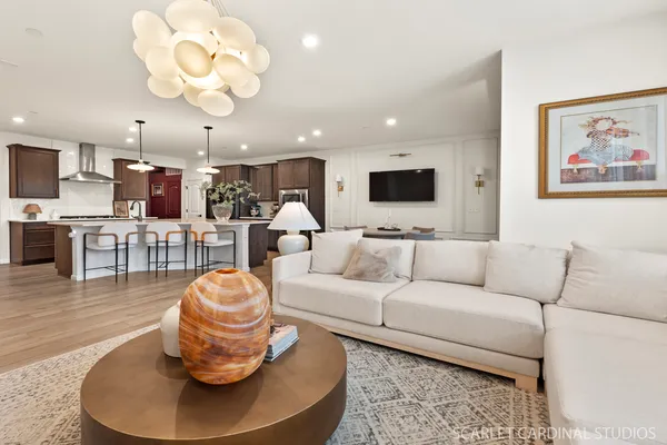 a living room with furniture kitchen view and a chandelier