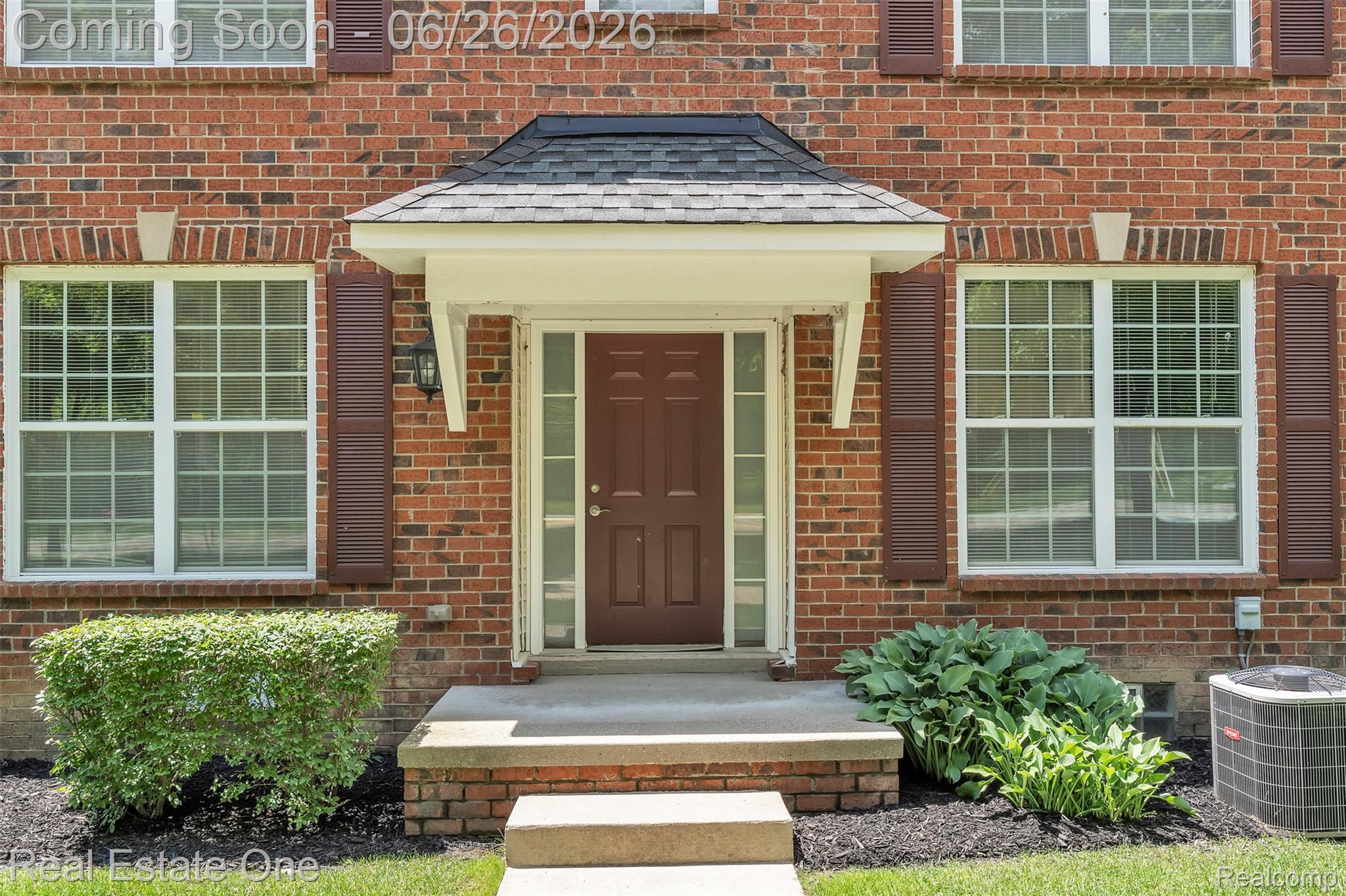 Brick facade residence featuring a covered entry, brown front door with sidelights, and a front porch with steps