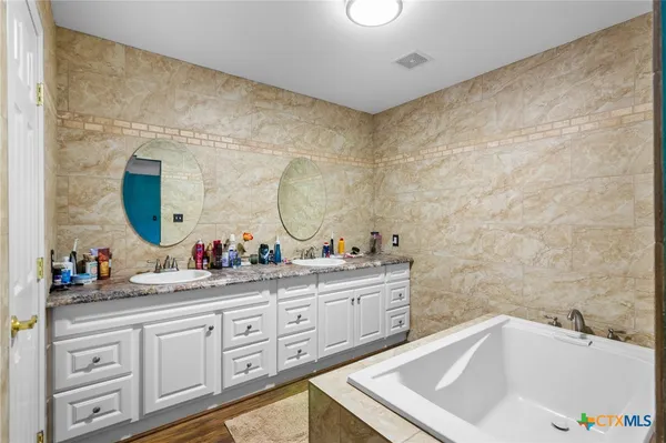 a bathroom with a double vanity sink mirror and bathtub