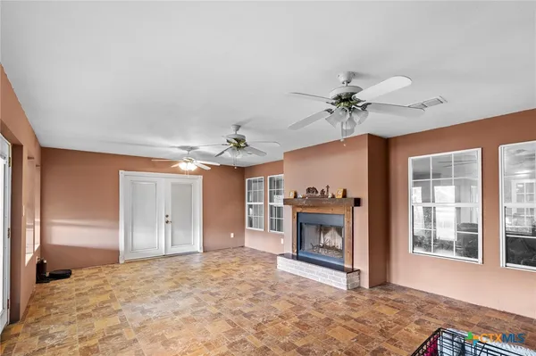a view of a livingroom with a fireplace a ceiling fan and wooden floor