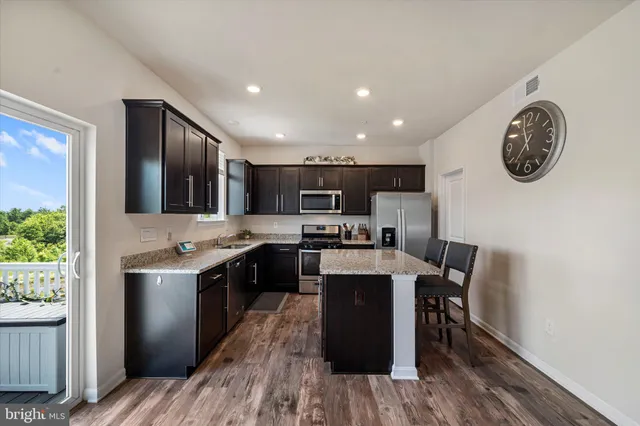 a kitchen with stainless steel appliances granite countertop a stove top oven a sink and a refrigerator