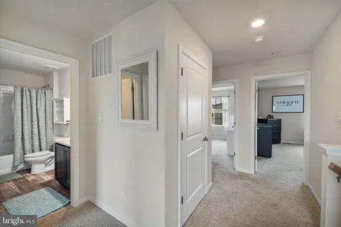 a view of a hallway with bathroom and wooden floor