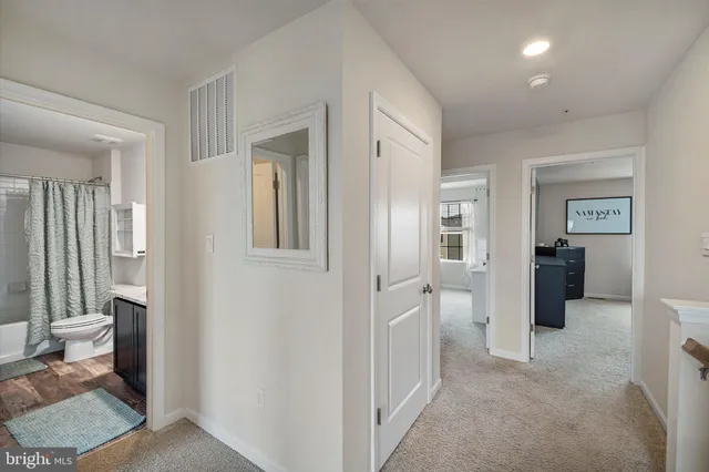 a view of a hallway with bathroom and wooden floor