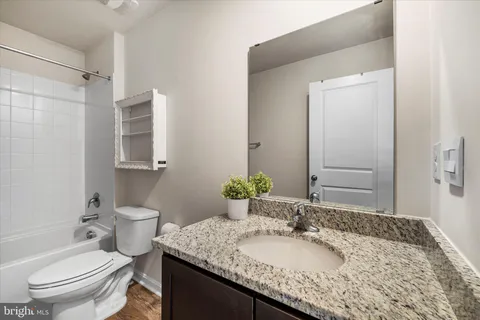 a bathroom with a granite countertop sink a toilet and a mirror
