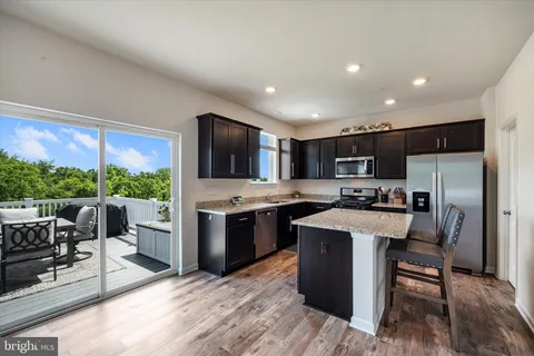 a kitchen with stainless steel appliances kitchen island granite countertop a stove refrigerator and a view of living room