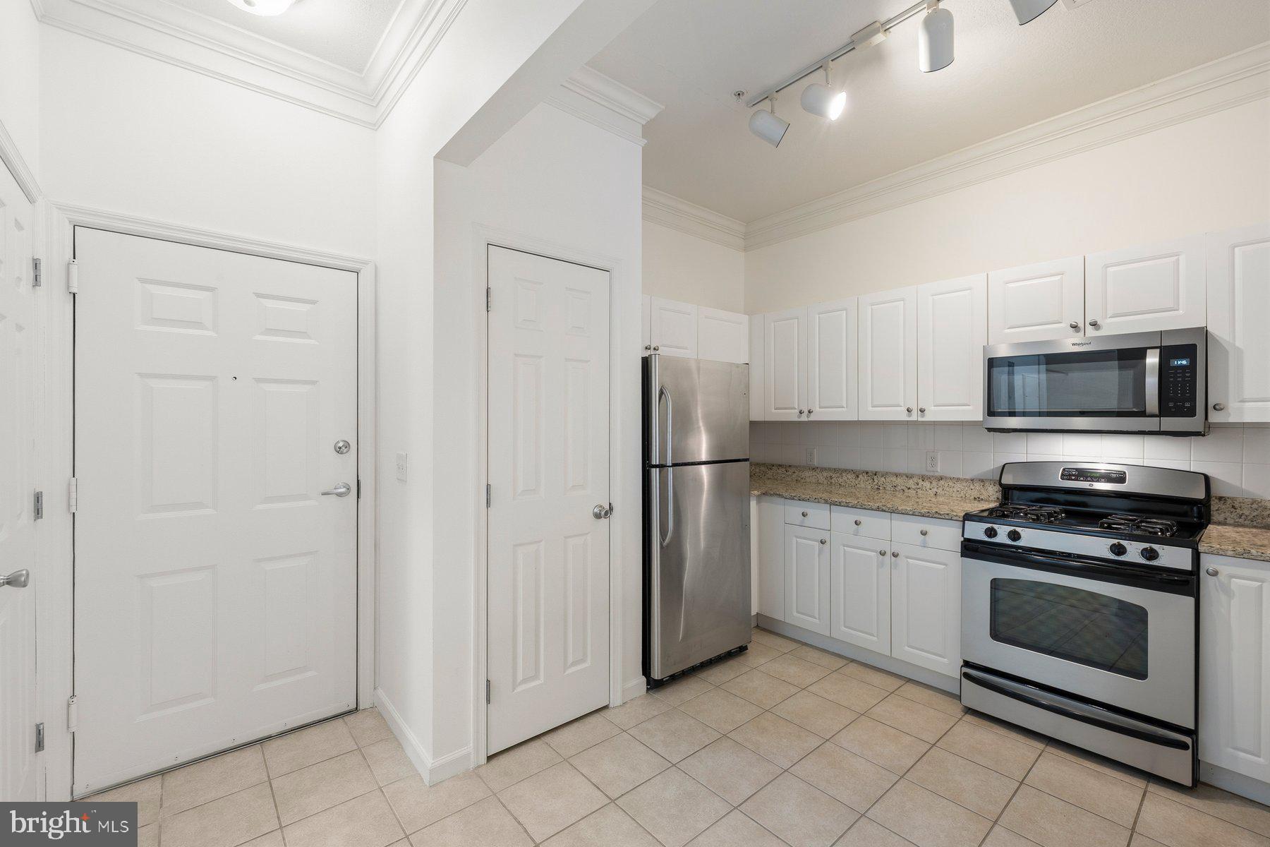 7 Booth Street, Unit 109 Gaithersburg, MD 20878 - Photo 7 of 28 a kitchen with white cabinets and stainless steel appliances