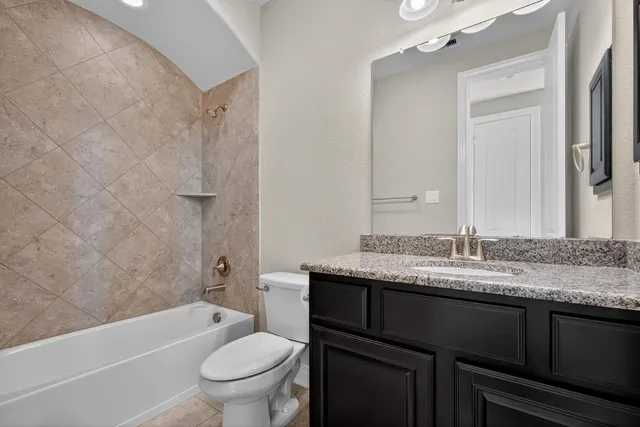 a bathroom with a granite countertop toilet a sink and a bathtub