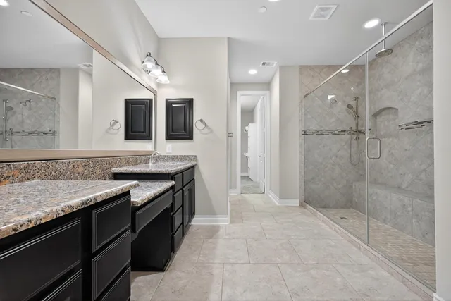 a bathroom with a granite countertop sink a mirror and shower