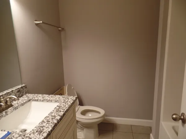 a bathroom with a granite countertop sink and a toilet
