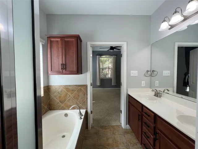 a en suite bathroom with a tub sink and mirror