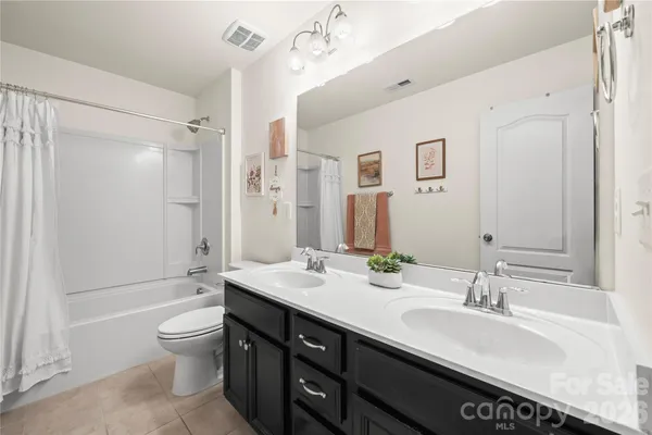a bathroom with a granite countertop sink toilet a large mirror a shower and a bathtub