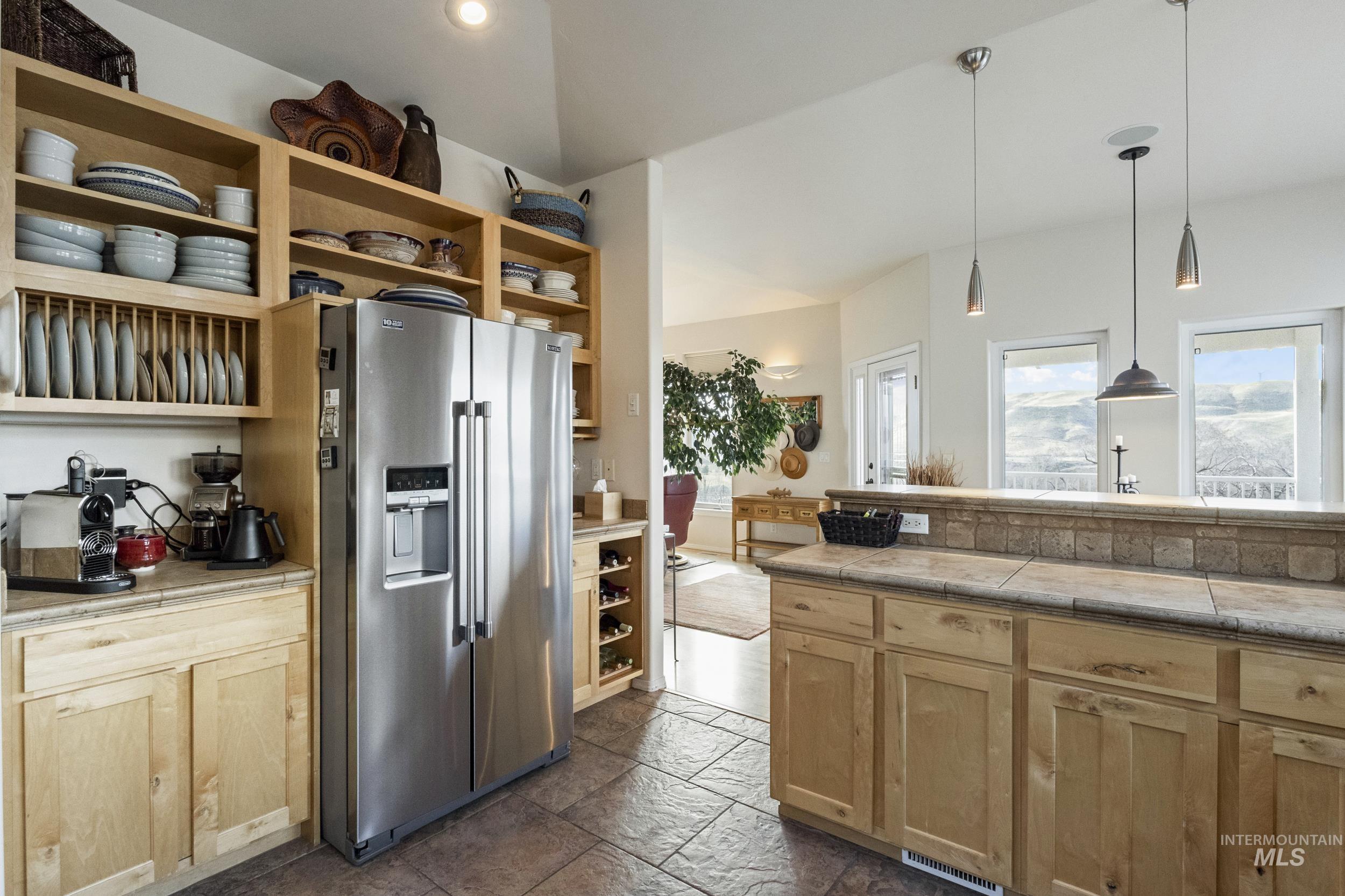 382 River Road Bliss, ID 83314 - Photo 11 of 46 Kitchen featuring high end fridge, stone tile floors, light wood finish cabinets, and decorative light fixtures